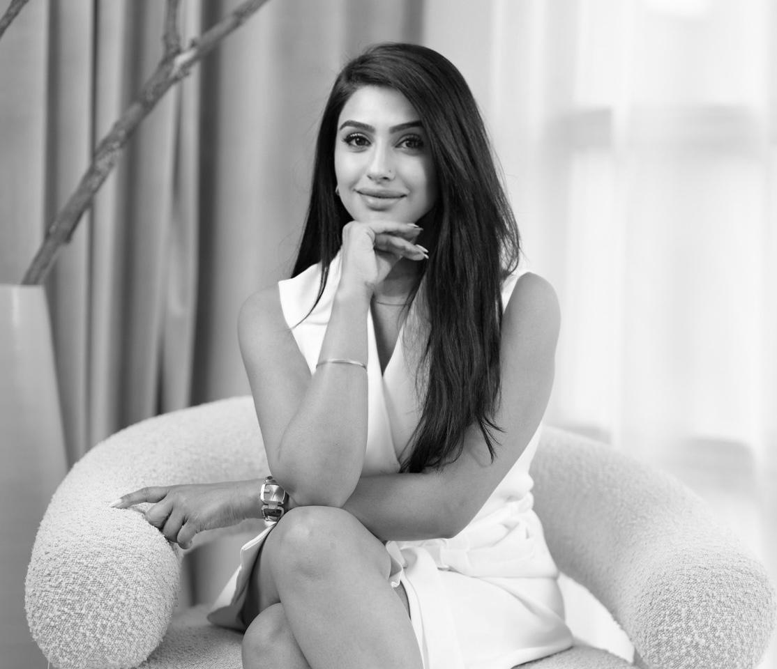 Black and white portrait of Kiran Gandhi seated on a cream boucle chair